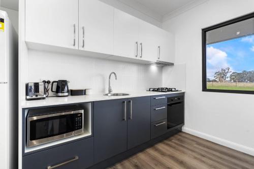 a kitchen with gray cabinets and a sink and a window at Glenowrie Cottage - 2 King Beds - Close to Cadia in Millthorpe