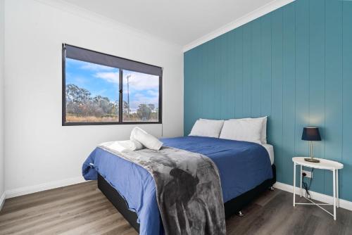 a blue bedroom with a bed and a window at Glenowrie Cottage - 2 King Beds - Close to Cadia in Millthorpe