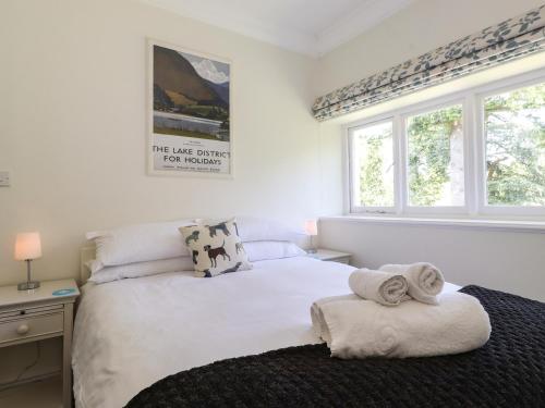 a bedroom with a white bed and two windows at Lake House Loft in Windermere