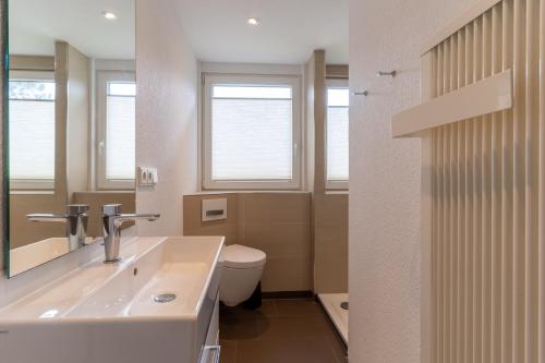 a bathroom with a sink and a toilet and windows at Reetdachhaus Dünen Lounge in Böhl