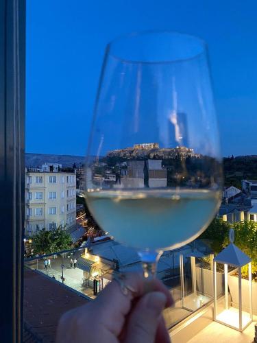 a person holding a glass of wine in front of a window at MiraMe Athens Boutique Hotel in Athens