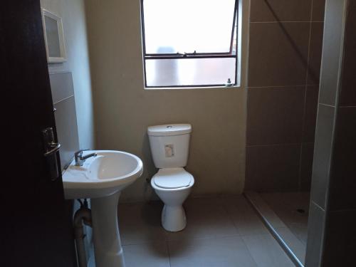 baño con aseo y lavabo y ventana en Lux contractors accommodation, en Bronkhorstspruit