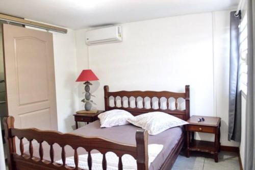 1 dormitorio con cama de madera y ventana en bungalow avec piscine chauffée., en Saint-Joseph
