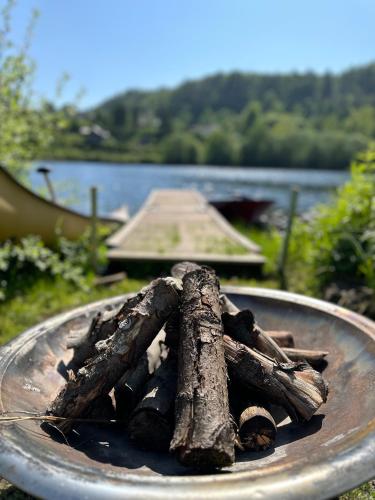 a pile of logs on a plate next to a lake at Glamping on idyllic lake, paddle boards & rowboat in Porsgrunn
