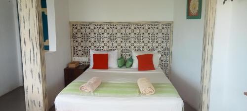 Un dormitorio con una cama blanca con almohadas rojas y verdes en Toddy by windy, en Unawatuna