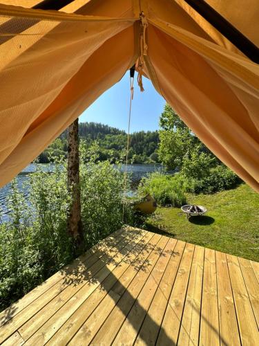 a tent on a deck with a view of a lake at Glamping on idyllic lake, paddle boards & rowboat in Porsgrunn