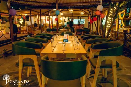 a restaurant with a long table and green chairs at Jacaranda Tree Garden in Pātan