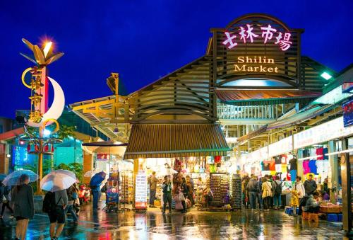 a crowd of people walking around a market at night at Riyuexing Hotel in Taipei