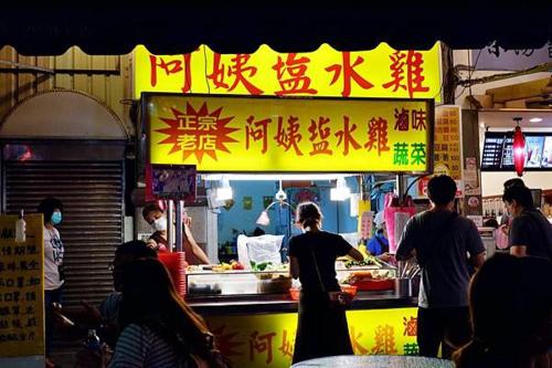 a group of people standing around a food stand at H Hotel in Taipei