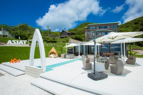 a pool with umbrellas and chairs next to a house at Jukaitei in Kyotango