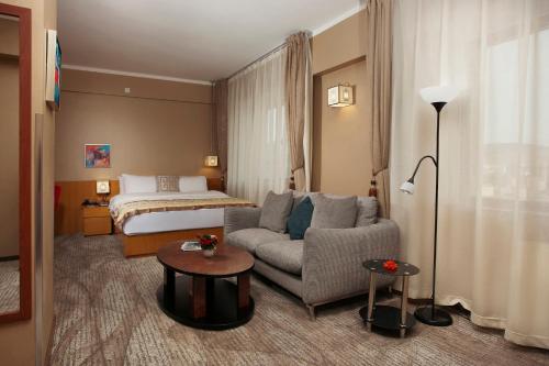 a hotel room with a couch and a bed at Ramada Ulaanbaatar City Center in Ulaanbaatar