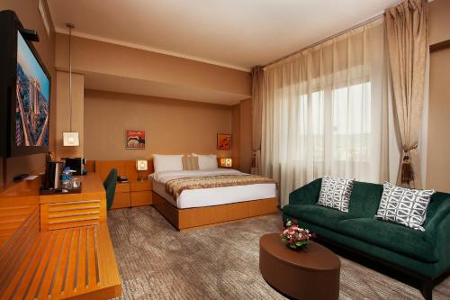 a hotel room with a bed and a green couch at Ramada Ulaanbaatar City Center in Ulaanbaatar