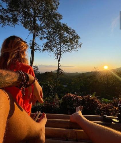 two people sitting on a ledge watching the sunset at Wanagiri Campsite in Gitgit