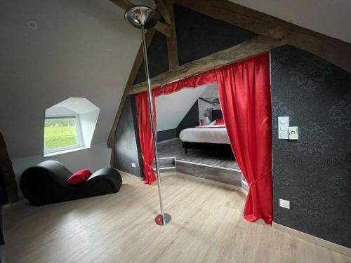 a attic room with a bed with red curtains at Love room le temps d'un plaisir in Landisacq