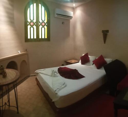 a bedroom with a bed with red pillows and a window at Atlas Resorts in Aït Ourir