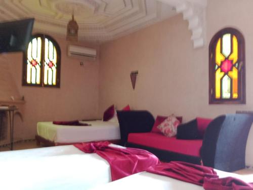 a room with two beds and a couch and stained glass windows at Atlas Resorts in Aït Ourir