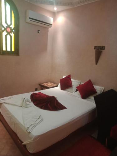 a bedroom with a bed with red pillows and a window at Atlas Resorts in Aït Ourir