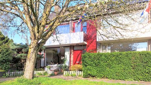 a red house with a tree in front of it at Bennebroek B&B in Bennebroek