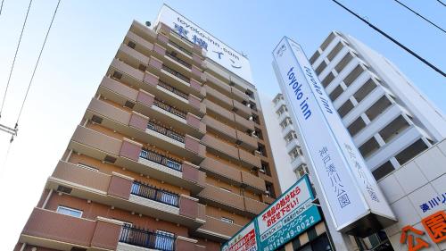 a tall building with street signs in front of it at Toyoko Inn Kobe Minatogawa Koen in Kobe