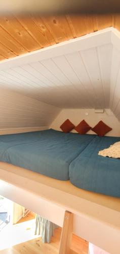 Cama en habitación elevada con techo de madera en Sjönära liten stuga med sovloft, toilet in other small house, no shower en Åkersberga