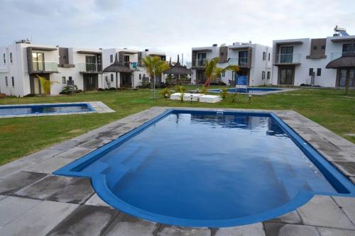 una imagen de una piscina frente a algunos apartamentos en Green Village Duplex, en Grand Gaube