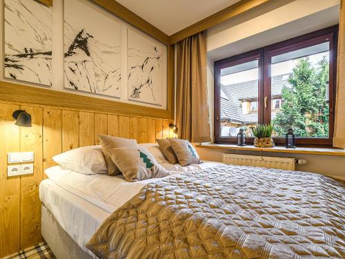 a bedroom with a large bed and a window at VisitZakopane - Willa Bajka Apartments in Zakopane