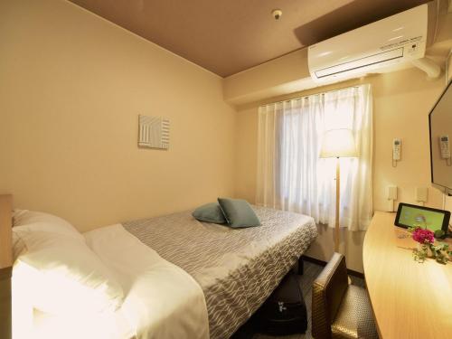 ein Hotelzimmer mit einem Bett und einem Fenster in der Unterkunft Yokohama Heiwa Plaza Hotel in Yokohama