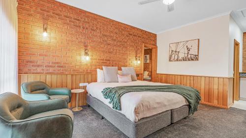 a hotel room with a bed and two chairs at Golden River Motor Inn in Moama