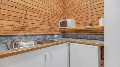 a kitchen with a sink and a brick wall at Golden River Motor Inn in Moama