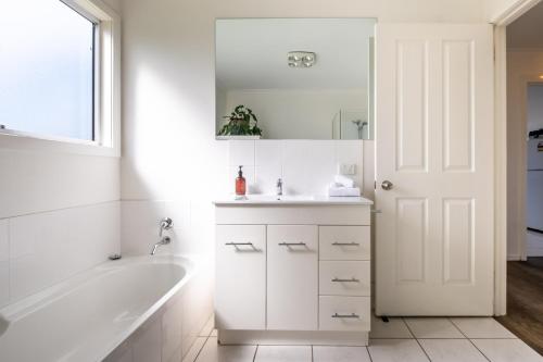 a white bathroom with a tub and a sink at Eagles Rest in Coles Bay