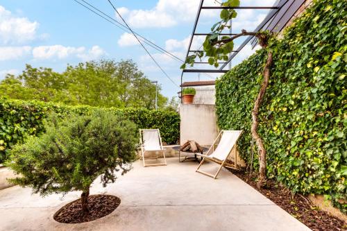 two chairs and a tree on a sidewalk next to a hedge at Modern holiday home with terrace close to Nova Gorica in Miren