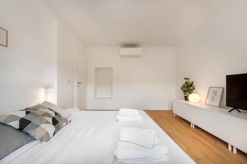 a white bedroom with a bed and a tv at Modern holiday home with terrace close to Nova Gorica in Miren