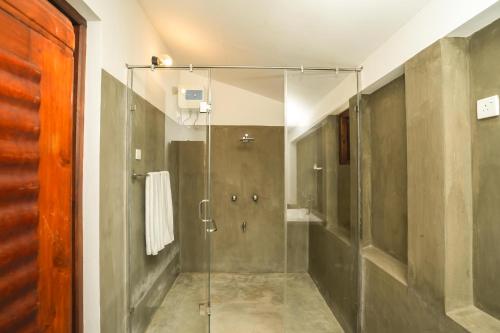 W łazience znajduje się prysznic ze szklanymi drzwiami. w obiekcie Malala Retreat w mieście Hambantota