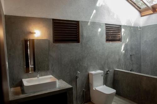 a bathroom with a white toilet and a sink at Mambo’s hotel Arugam Bay in Pottuvil