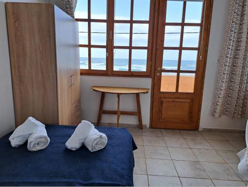 een slaapkamer met een bed, een tafel en een raam bij Nettuno Seafront Apartments in Análipsis