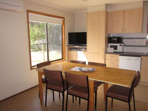a kitchen with a wooden dining table and chairs at Beachcomber Bliss in Smiths Beach