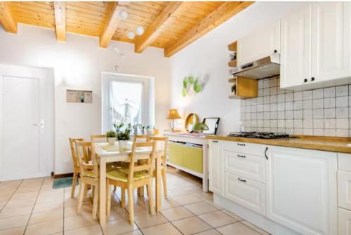 eine Küche mit weißen Schränken sowie einem Tisch und Stühlen in der Unterkunft B&B Ai Tigli in Udine