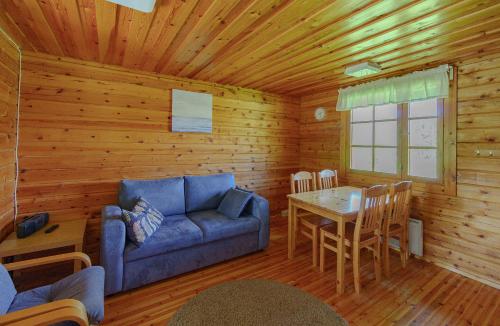 a living room with a blue couch and a table at Rauhalahti Holiday Cottages in Kuopio