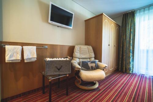 ein Hotelzimmer mit einem Stuhl und einem TV in der Unterkunft Alpenherz Apartments in Sankt Gallenkirch