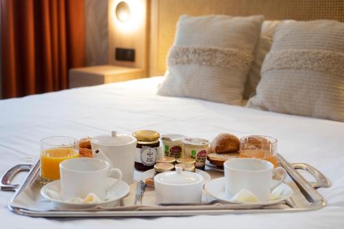 a tray of breakfast food on a bed at Kyriad Prestige Hotel Clermont-Ferrand in Clermont-Ferrand