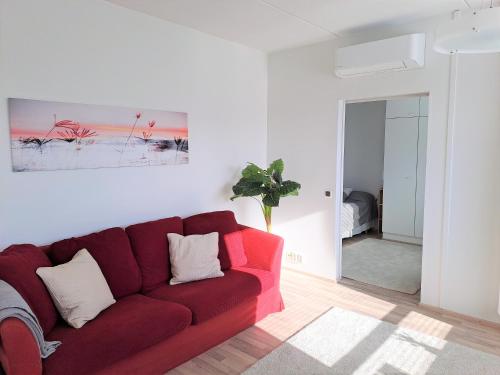 a living room with a red couch and a mirror at Saunallinen kaksio ilmastoinnilla ja autopaikalla! in Oulu