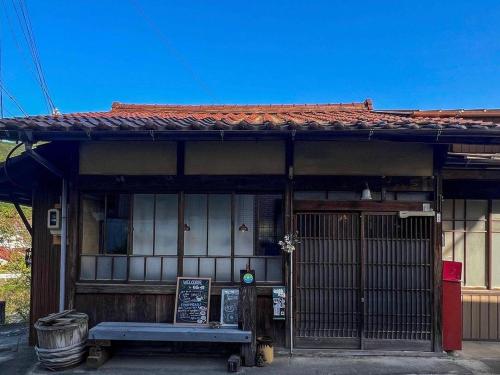 un edificio con un banco delante de él en ゲストハウス　にじゅうよん, en Sakashita