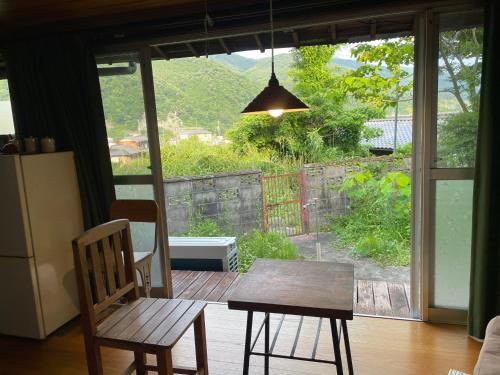 una mesa y sillas en una habitación con vistas a un patio en ゲストハウス　にじゅうよん, en Sakashita