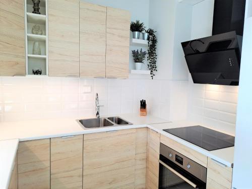 a kitchen with wooden cabinets and a sink at Saunallinen kaksio ilmastoinnilla ja autopaikalla! in Oulu