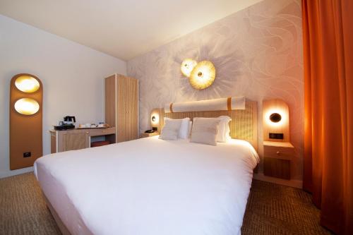 a bedroom with a large white bed in a room at Kyriad Prestige Hotel Clermont-Ferrand in Clermont-Ferrand
