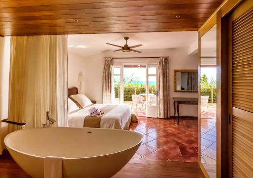 サン・ルにあるBlue Margouillat Seaview Hotel-RELAIS & CHATEAUXのバスルーム(バスタブ付)、ベッドルーム(ベッド付)が備わります。