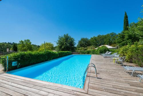 a swimming pool with chairs and a wooden deck at Natura Lodge in Barjac