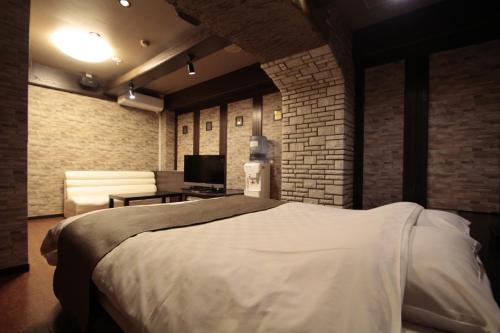 a bedroom with a large bed and a brick wall at ホテルロペ39 大人専用 in Nagoya