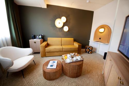 a living room with a couch and a table at Kyriad Prestige Hotel Clermont-Ferrand in Clermont-Ferrand