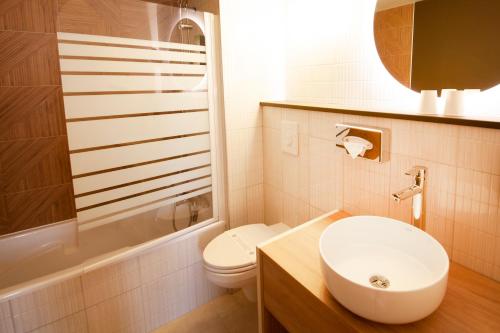 a white bathroom with a sink and a toilet at Kyriad Prestige Hotel Clermont-Ferrand in Clermont-Ferrand